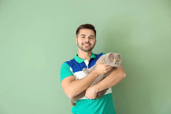 Giovane uomo con simpatico gatto divertente su sfondo di colore — Foto Stock