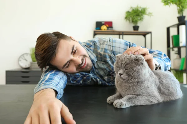 Young man with cute funny cat at home — Stock Photo, Image