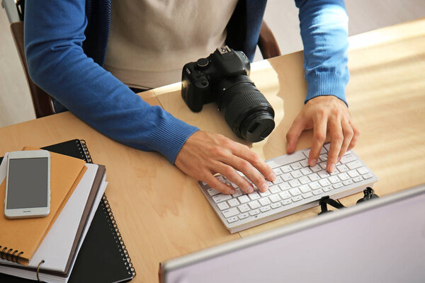 Мужской фотограф, работающий на компьютере в студии
