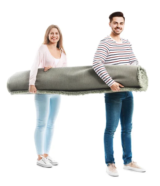 Young couple holding rolled carpet against white background — Stock Photo, Image