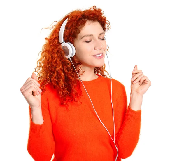 Mulher ruiva bonita ouvindo música no fundo branco — Fotografia de Stock