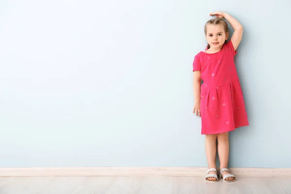 Kleines Mädchen misst Höhe nahe der Mauer — Stockfoto