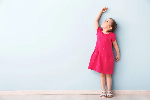Маленька дівчинка вимірює висоту біля стіни — стокове фото
