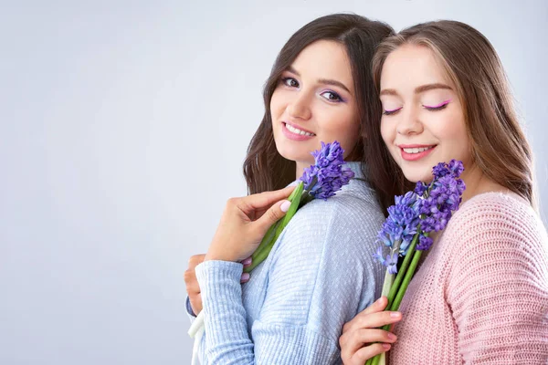 Krásné mladé ženy s hyacint květy na světlém pozadí — Stock fotografie