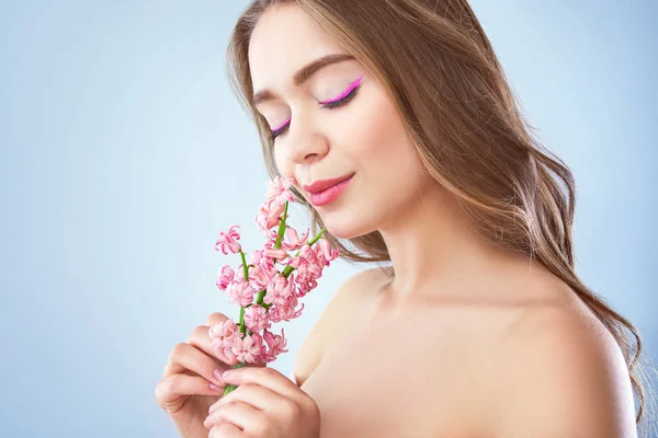 Vacker ung kvinna med hyacint blommor på ljus bakgrund — Stockfoto