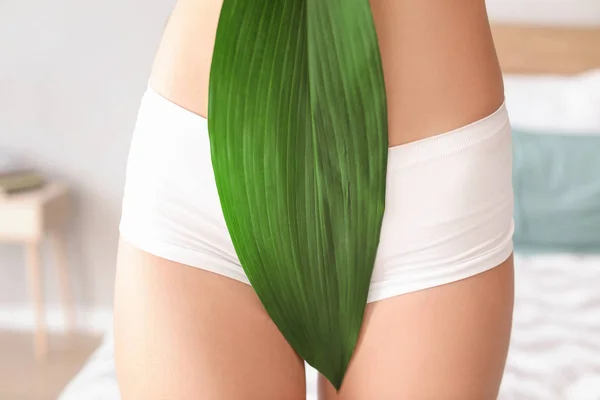 Mooie jonge vrouw in ondergoed en met groen blad thuis, close-up — Stockfoto