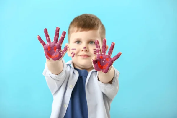 Funny little boy with hands and face in paint on color background — Stock Photo, Image