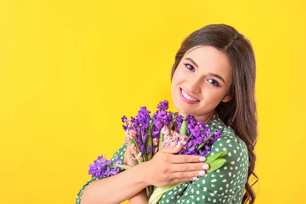Vacker ung kvinna med hyacint blommor på färg bakgrund — Stockfoto