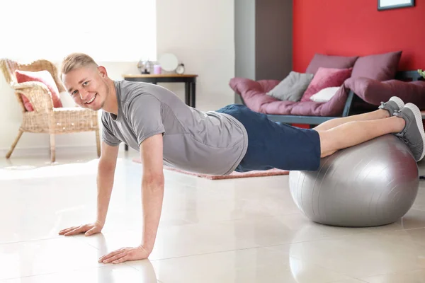 Young man doing exercise with fitball at home — Stock Photo, Image