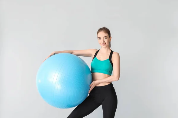 Young sporty woman with fitball on grey background — Stock Photo, Image