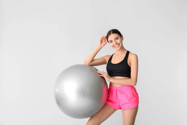 Young sporty woman with fitball on grey background — Stock Photo, Image