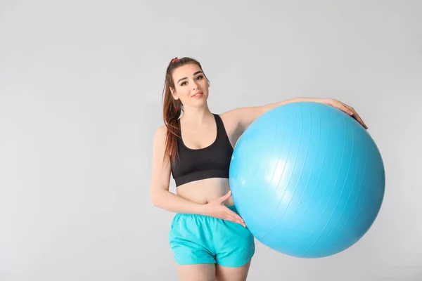 年轻的运动女人与灰色背景的健身球 — 图库照片