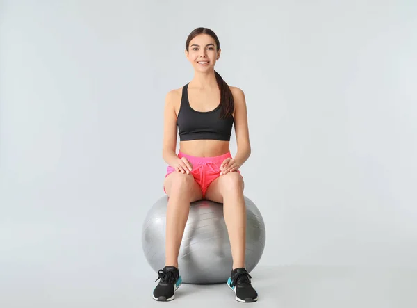 Joven mujer deportiva con fitball sobre fondo gris — Foto de Stock