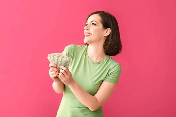 Щаслива молода жінка з грошима на кольоровому фоні — стокове фото