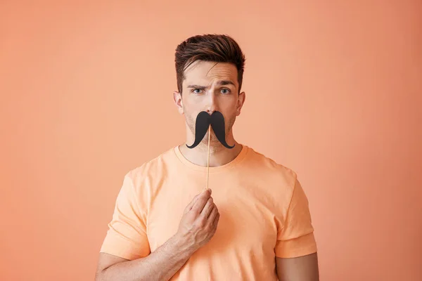 Funny portrait of handsome man with fake mustache on color background — Stock Photo, Image