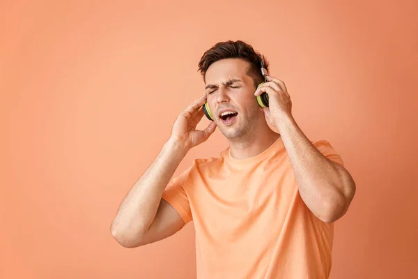 Portrét pohledného muže naslouchajícího hudbě na barevném pozadí — Stock fotografie