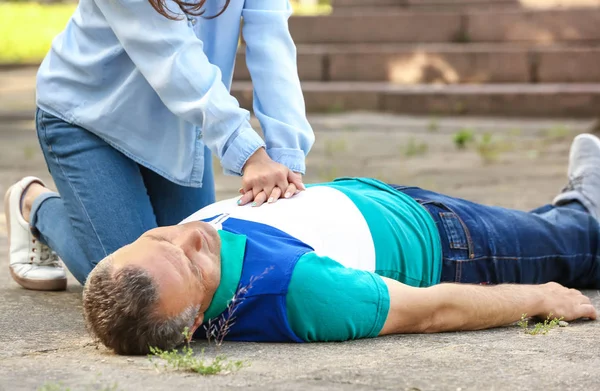 Vrouwelijke passer-door het doen van CPR op bewusteloze volwassen man buitenshuis — Stockfoto