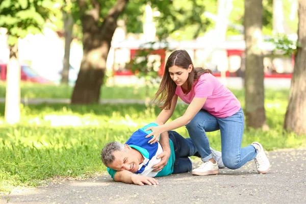 Female passer-by helping mature man who is having heart attack outdoors — Stock Photo, Image