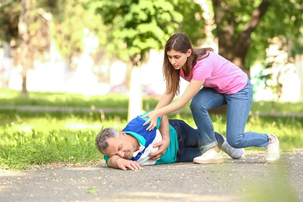 Female passer-by helping mature man who is having heart attack outdoors — Stock Photo, Image