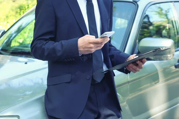 Страховий агент з мобільним телефоном біля автомобіля на дорозі — стокове фото