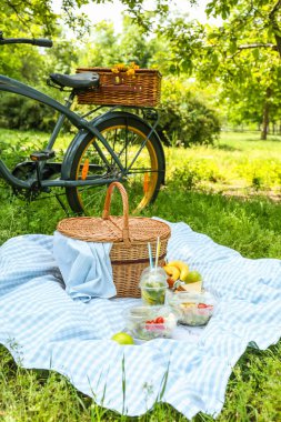 Parkta romantik piknik için lezzetli yiyecek ve içecek ile bisiklet ve hasır sepeti