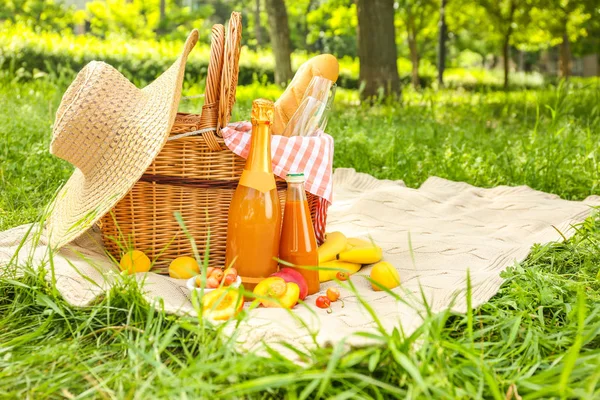 Cesto di vimini con cibi e bevande gustosi per un romantico picnic nel parco — Foto Stock