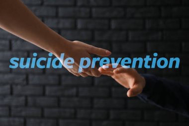 Woman giving hand to depressed man against dark background. Suicide prevention concept clipart