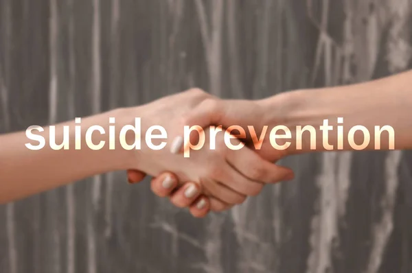 Women holding hands on grey background. Suicide prevention concept — Stock Photo, Image