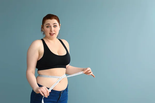 Надмірна вага жінки з вимірювальною стрічкою на кольоровому фоні. Концепція втрати ваги — стокове фото