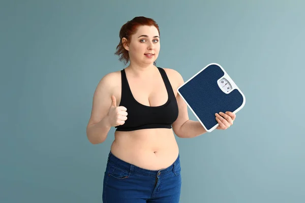 Overweight woman with scales showing thumb-up on color background. Weight loss concept — Stock Photo, Image