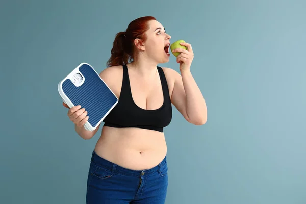 Overweight woman with scales and apple on color background. Weight loss concept — Stock Photo, Image
