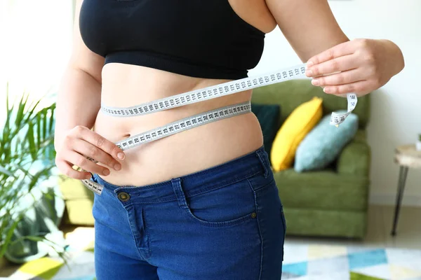 Mujer con sobrepeso y cinta métrica en casa. Concepto de pérdida de peso —  Fotos de Stock