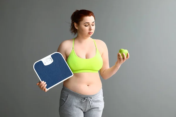 Mujer con sobrepeso con escamas y manzana sobre fondo gris. Concepto de pérdida de peso — Foto de Stock