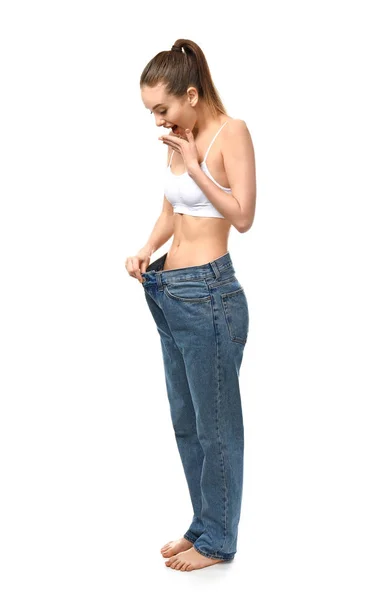 Stock image Happy young woman in loose jeans on white background. Weight loss concept