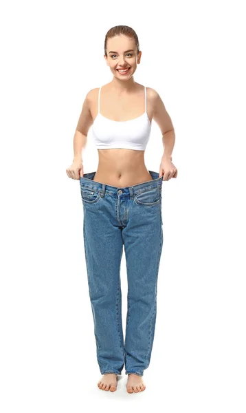 Μια νεαρή γυναίκα με φαρδιά τζιν σε λευκό φόντο. Έννοια απώλειας βάρους — Φωτογραφία Αρχείου