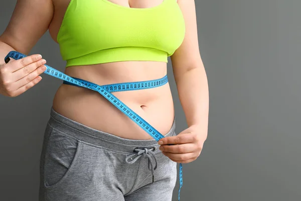 グレーの背景に測定テープで太りすぎの女性。減量の概念 — ストック写真