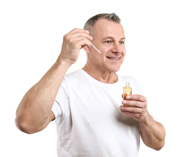 Bonito homem de meia-idade com garrafa de soro para cuidados com a pele em fundo branco — Fotografia de Stock