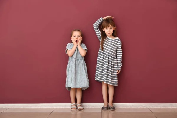 Little girls measuring height near wall — Stock Photo, Image