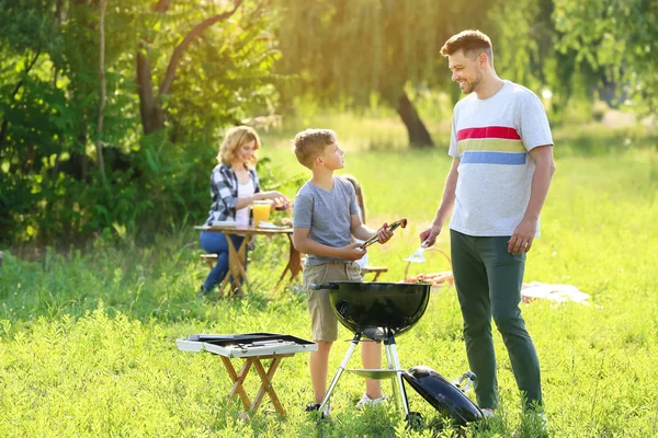 Otec se synem vaří chutné jídlo na grilu venku — Stock fotografie