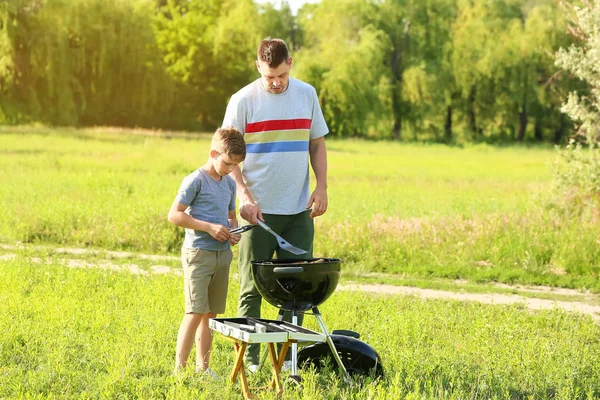 Padre con hijo cocina sabrosa comida en la parrilla al aire libre —  Fotos de Stock