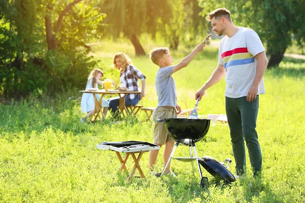 Father with son cooking tasty food on grill outdoors — Stock Photo, Image