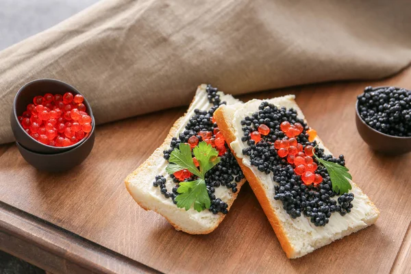 Sandwiches con caviar negro y rojo sobre tabla de madera — Foto de Stock