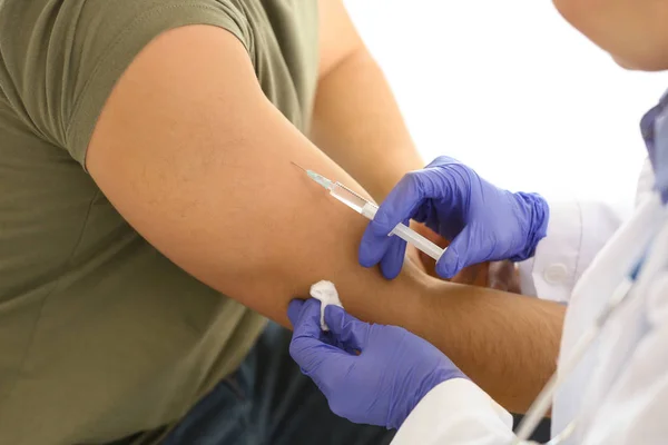 Doktor vaccinerar ung man på kliniken — Stockfoto