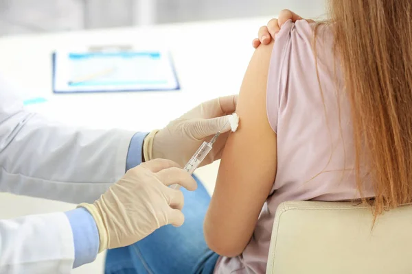 Doctor vaccinating young woman in clinic — Stock Photo, Image