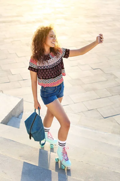 Beautiful young woman on roller skates taking selfie outdoors — Stock Photo, Image