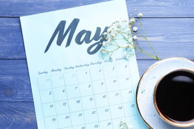 Ahşap arka planda kağıt takvimi, fincan kahve ve çiçekler