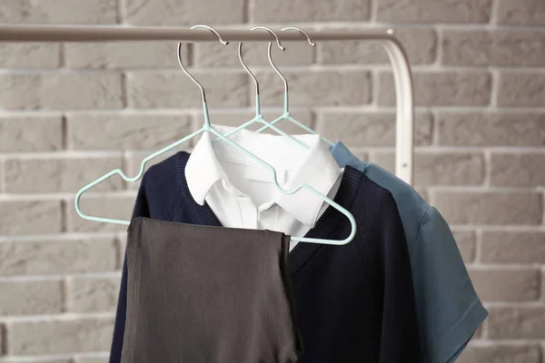 Stylish school uniform hanging on rack against brick wall — Stock Photo, Image