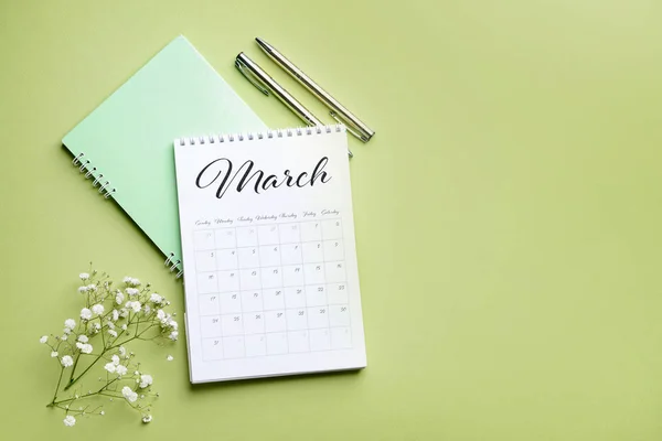 Vänd papper kalender, anteckningsbok och blommor på färg bakgrund — Stockfoto