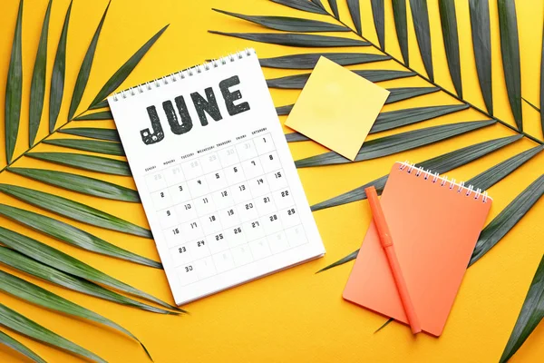 Flip calendario di carta, quaderno e foglie tropicali su sfondo a colori — Foto Stock