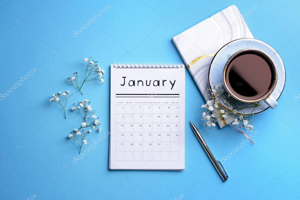 Flip paper calendar, cup of coffee and notebook on color background
